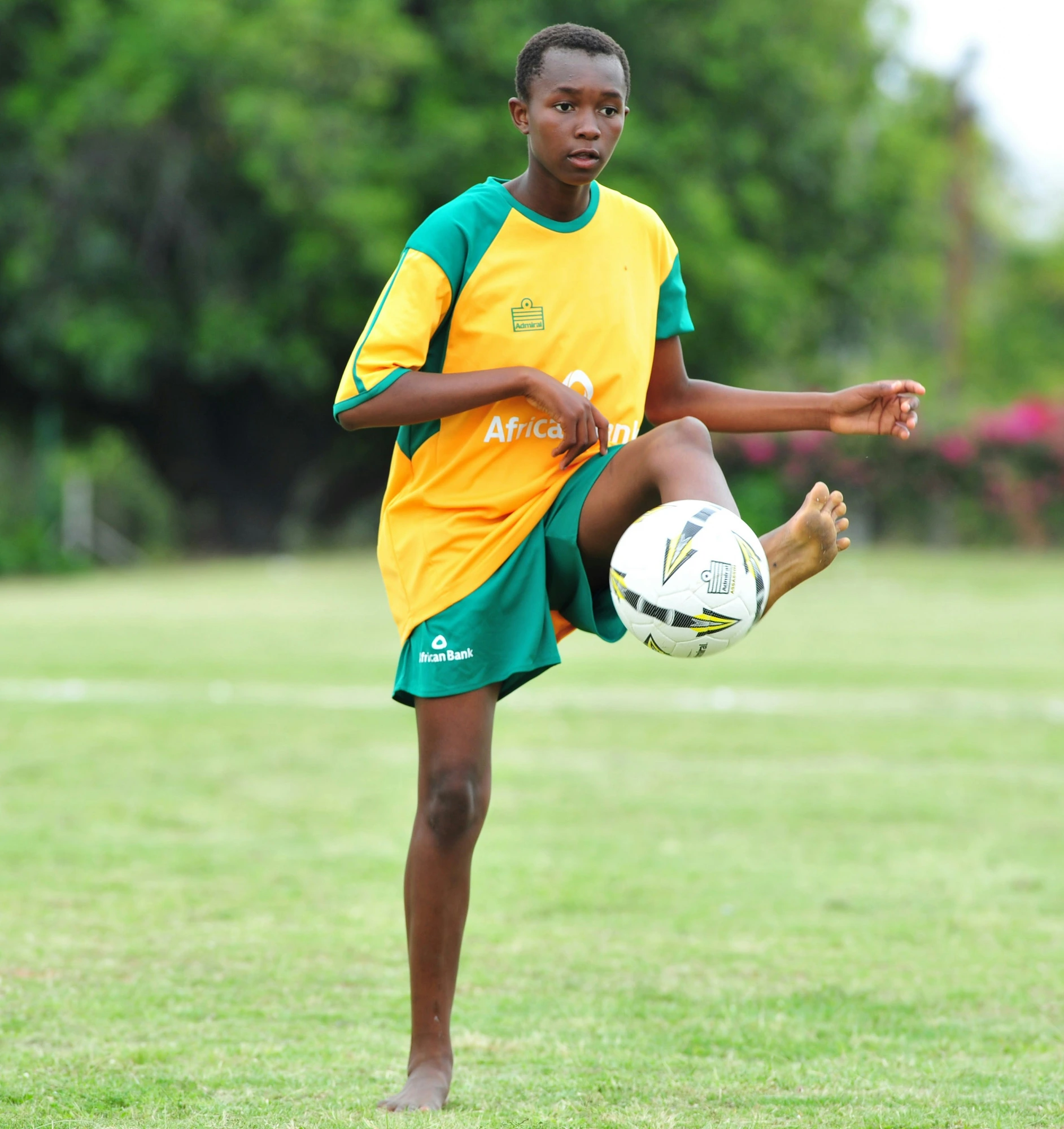 Young footballer juggling ball in yellow-green jersey