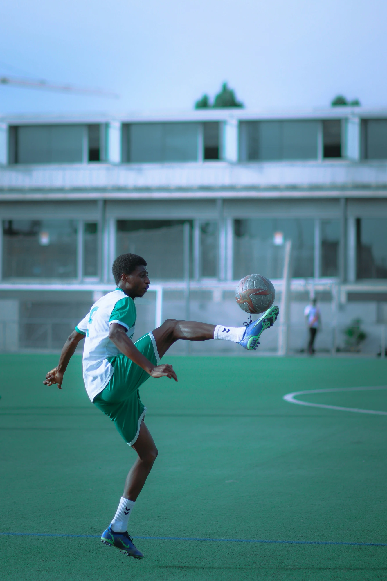 Young footballer in green kit controlling the ball