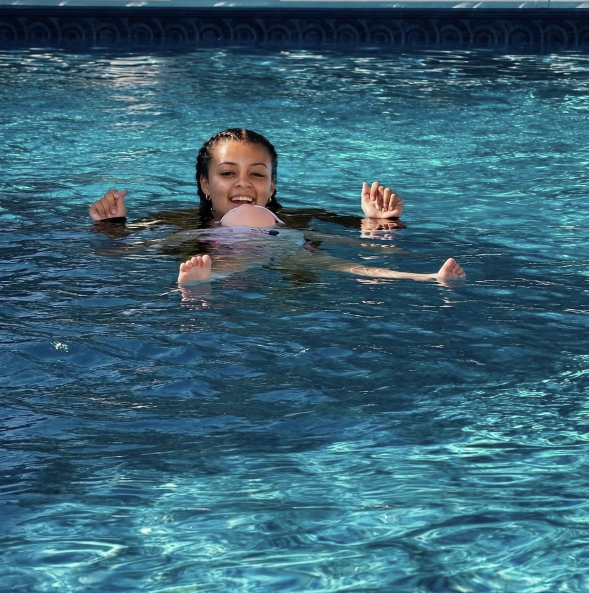 Coach and toddler with fish toys in a calm indoor pool