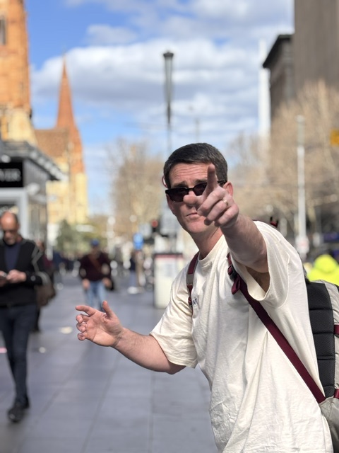 Martin, sunglasses on, pointing out a Melbourne detail mid-tour