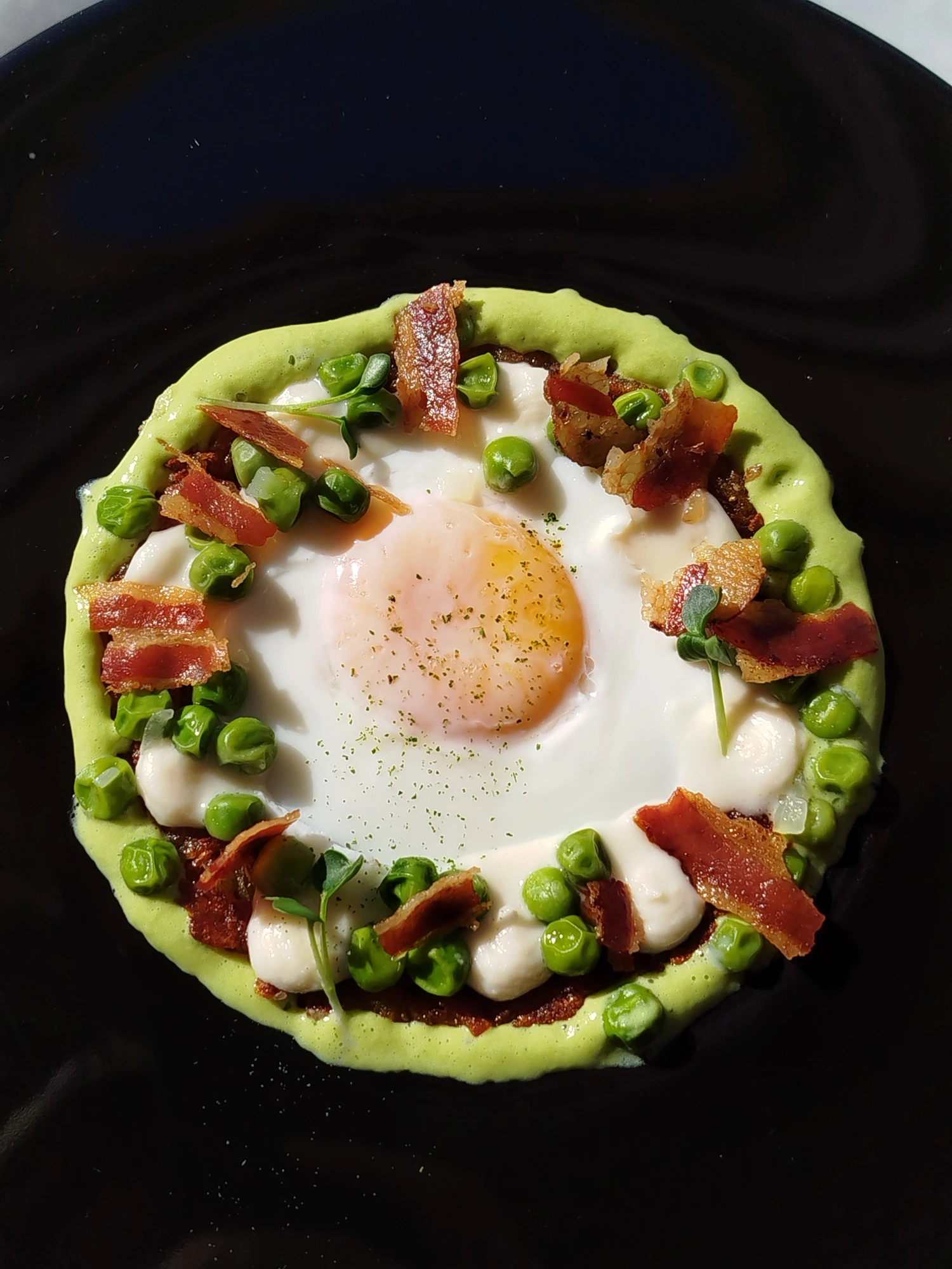 Uovo al vapore su rösti al peperoncino, spuma di piselli, grana padano e bacon croccante